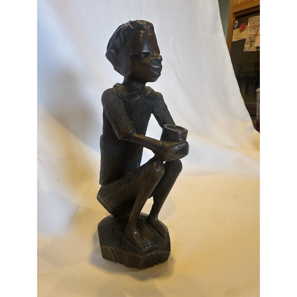 This is a vintage African wood carving of a seated figure Holding Medicine Bow